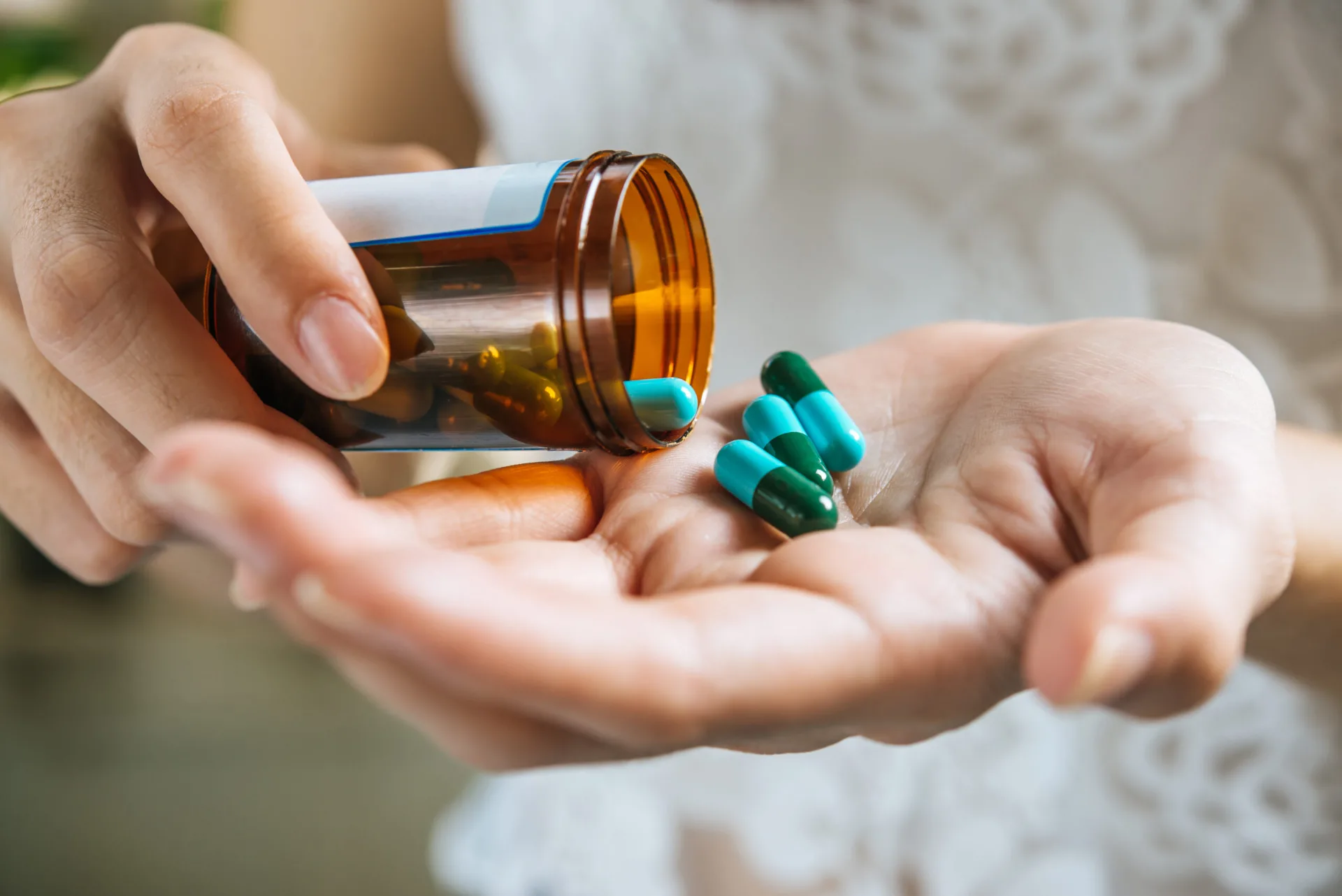 Hand pouring pills from a medicine bottle